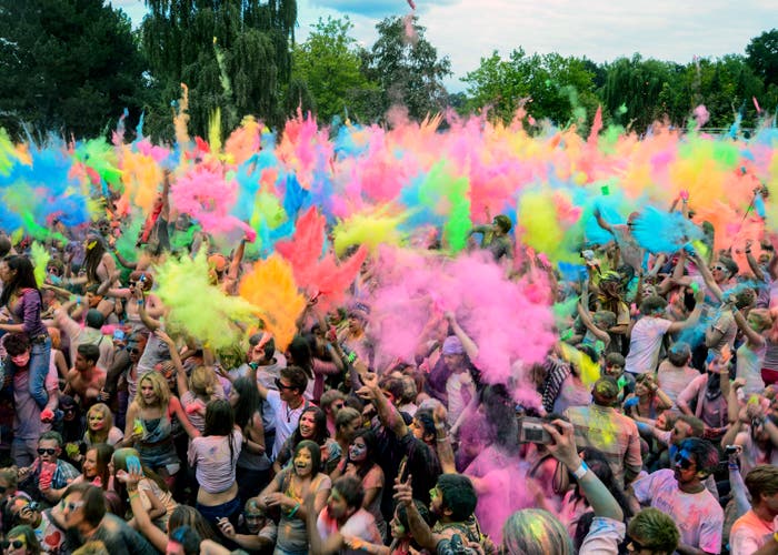 Multitud de gente tirándose globos de colores